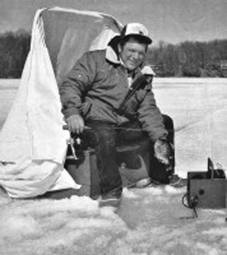 A younger Dave Genz smiles with a dandy bluegill, seated in an early Fish Trap, holding one of the first graphite ice rods. His wooden flasher box is beside the hole. A new book, Ice Revolution, chronicles the story of how this ancient sport was brought i